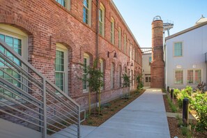 A brick building with a staircase, a pathway, and a small garden area with plants and bollards. - Hampton Inn Petaluma, CA (Petaluma)