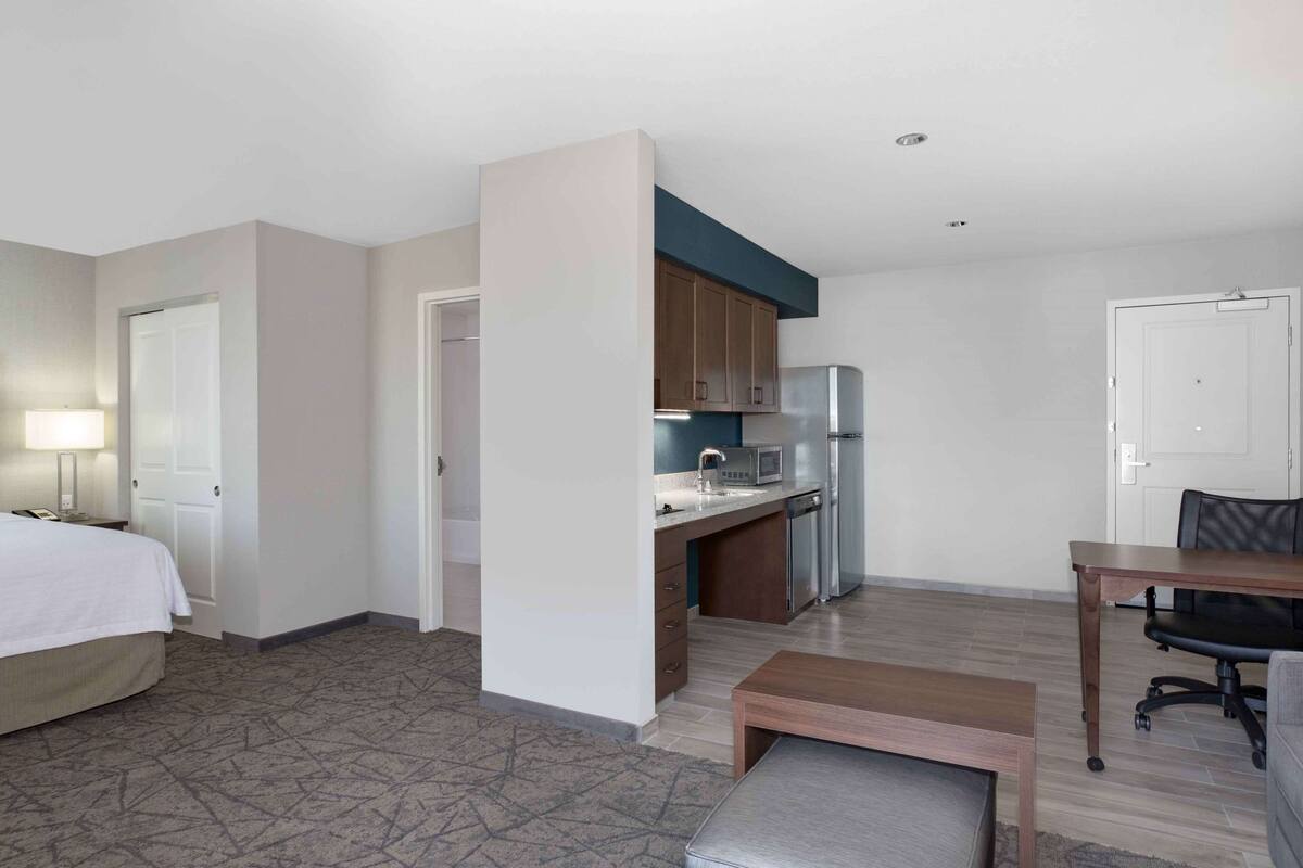 Una habitación de hotel compacta con cama, kitchenette y un pequeño comedor.