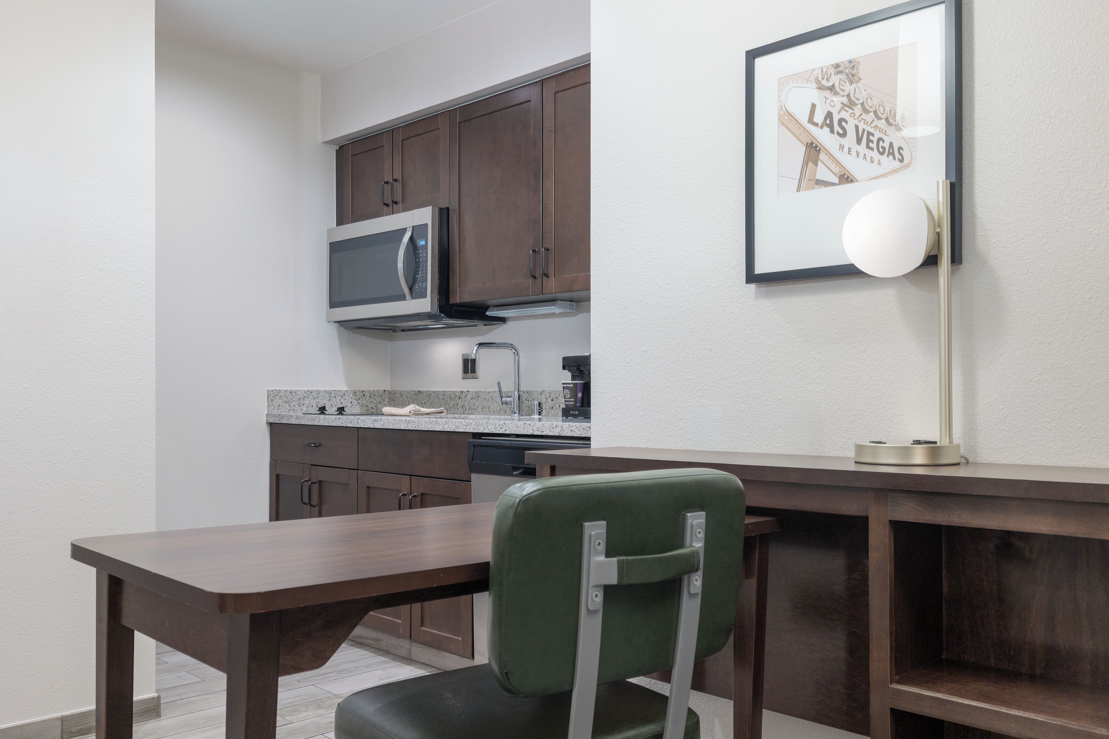 A compact kitchen with dark wooden cabinets, a microwave, a sink, and a coffee maker.