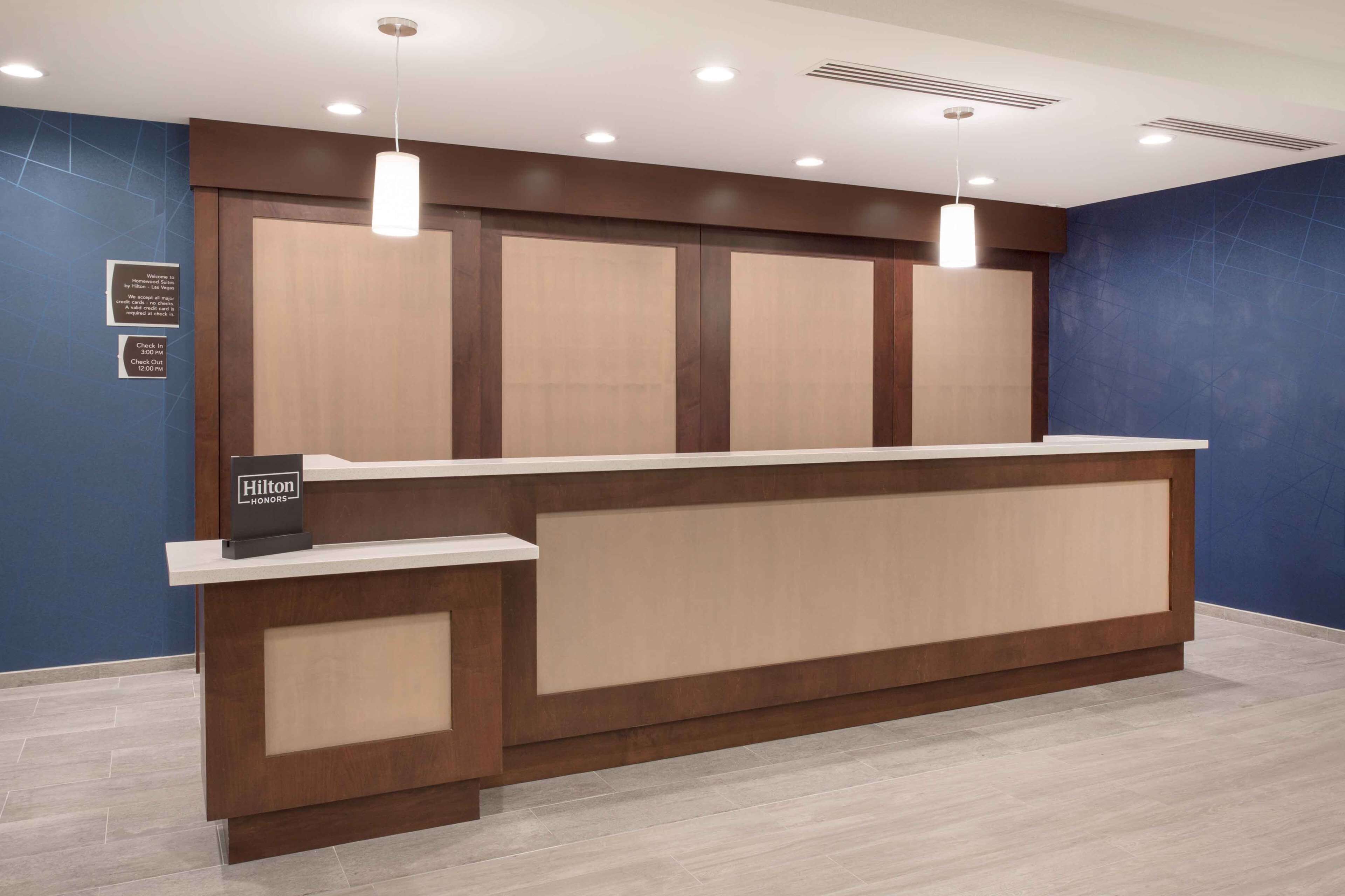 A hotel reception desk with a wooden finish, a check-in counter, and a sign indicating Hilton Honors.