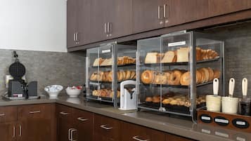 A bakery display case with various baked goods, a waffle maker, and a coffee machine.