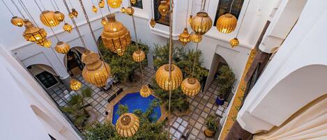 A courtyard with hanging lanterns, a pool, and greenery.