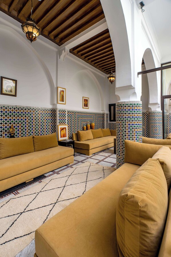 Un salón acogedor con dos sofás, paredes con diseño y techo de madera.