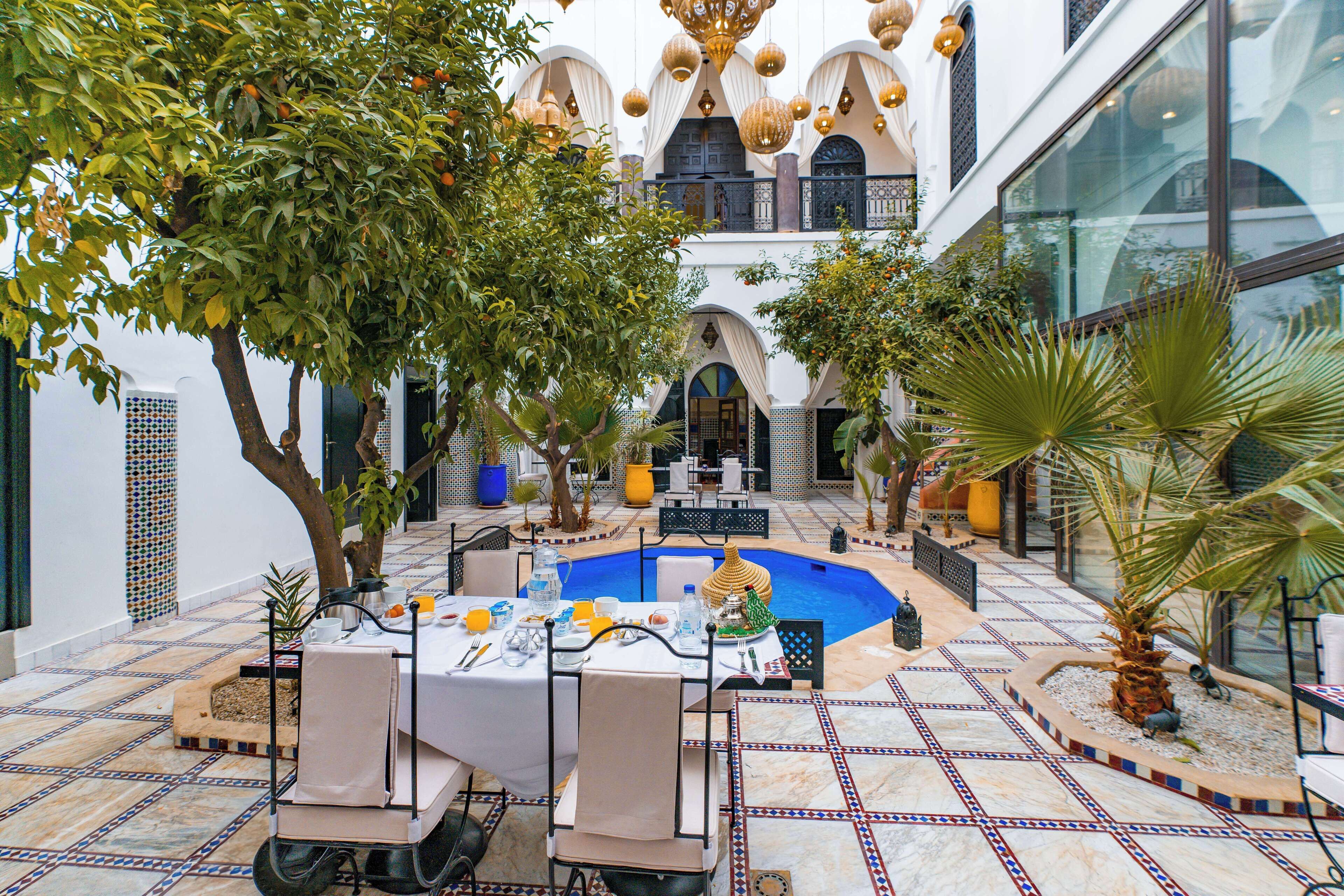 A courtyard with a pool, outdoor seating, and a dining area.
