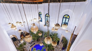 A multi-level atrium with hanging lanterns, a central blue pool, and potted plants. - Riad Dar Dialkoum (Marrakech)