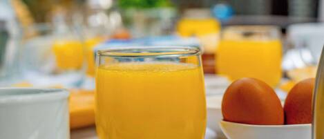 Una mesa de desayuno con jugo de naranja, huevos y una taza blanca.