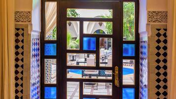 Una puerta con un diseño de vitral que da a un área exterior con piscina y asientos.