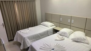 A hotel room with two beds, each with white bedding and a towel arranged in a fan shape. - Por do Sol Hotel (Santarém)