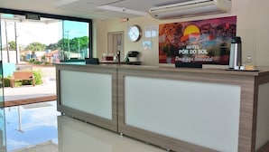 A hotel reception area with a reception desk, a clock, and a poster on the wall. - Por do Sol Hotel (Santarém)