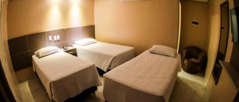 A hotel room with two beds, a bedside table, a chair, and an air conditioning unit.