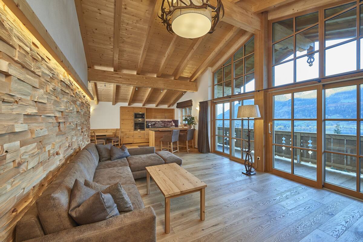 A spacious living area with a wooden ceiling, large windows, and a cozy sofa.