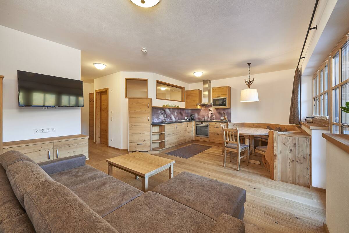 A modern living room with a sofa, a wooden coffee table, and a TV mounted on the wall.