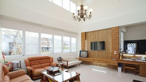 Amplia sala de estar con un sofá grande, una mesa de centro y un televisor instalado en una pared de madera.