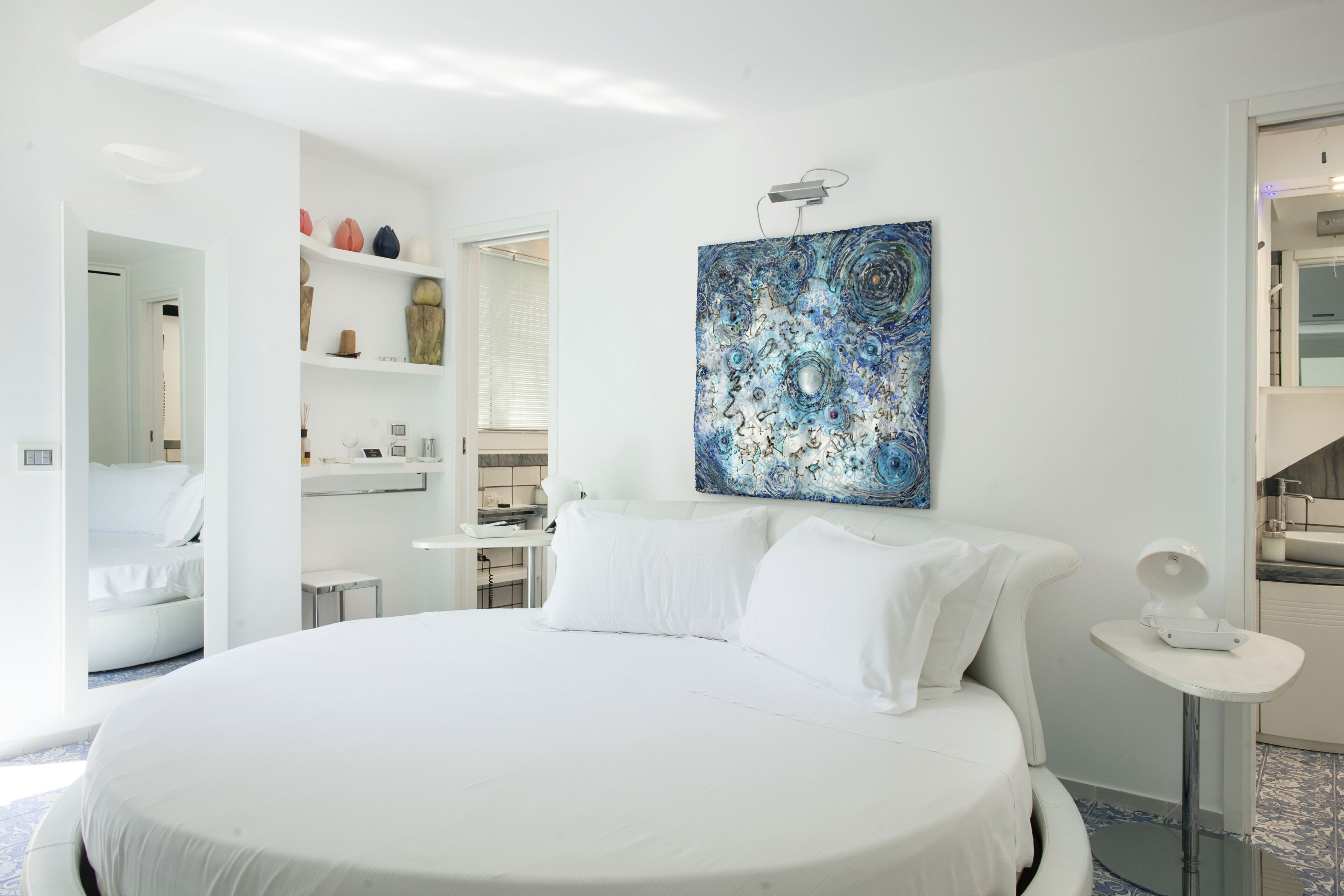 Un dormitorio moderno con una cama grande, una mesita de noche con lámpara y una obra de arte en la pared.
