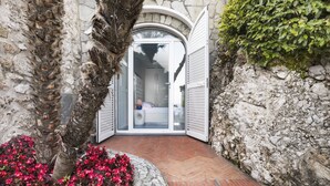 Un sendero de piedra que conduce a la entrada con puerta de vidrio de una habitación con cama y mesita de noche.