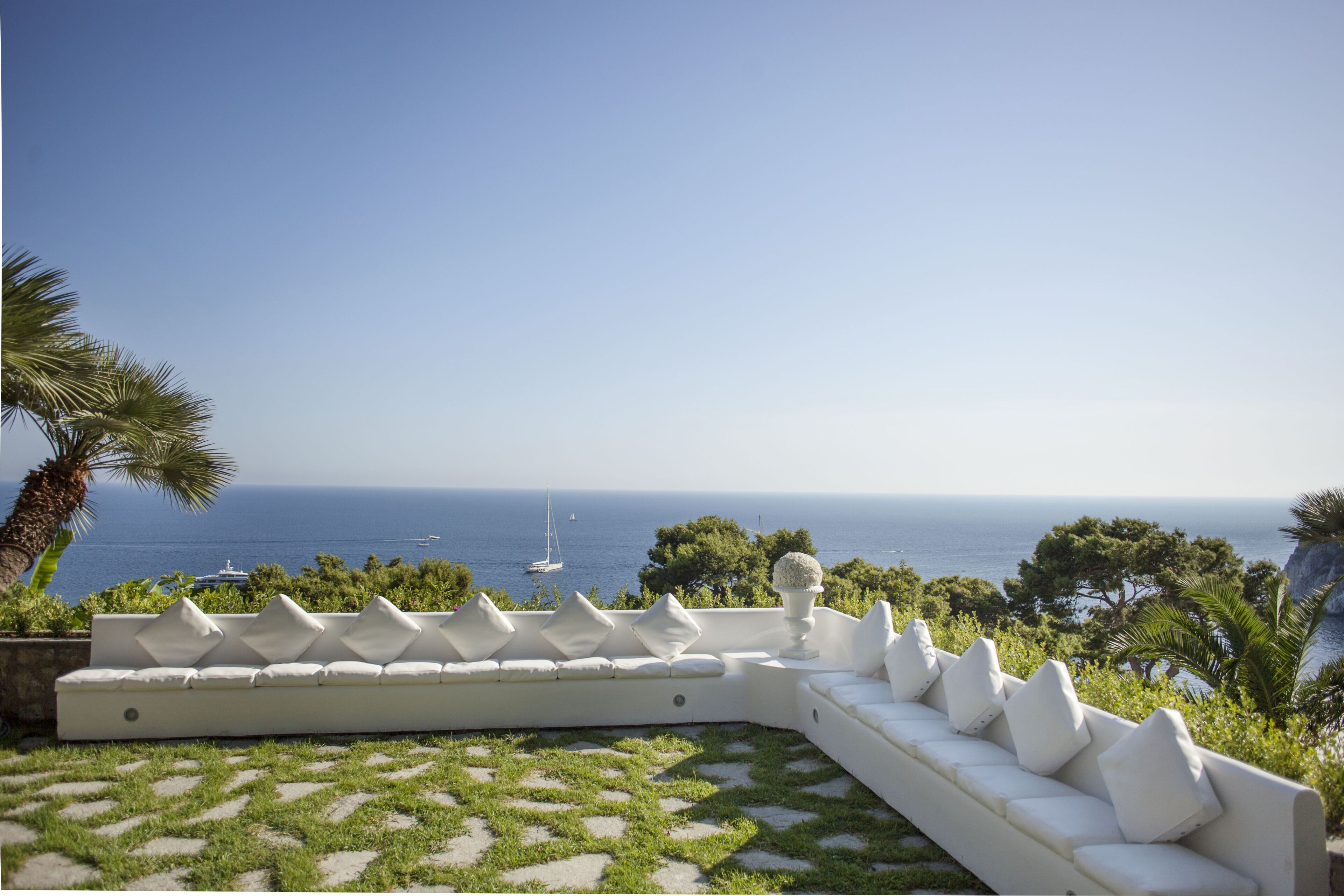 Un espacio exterior con asientos blancos y vistas al mar y a las embarcaciones.