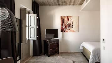 A bedroom with a bed, a dresser, a television, and a painting on the wall.