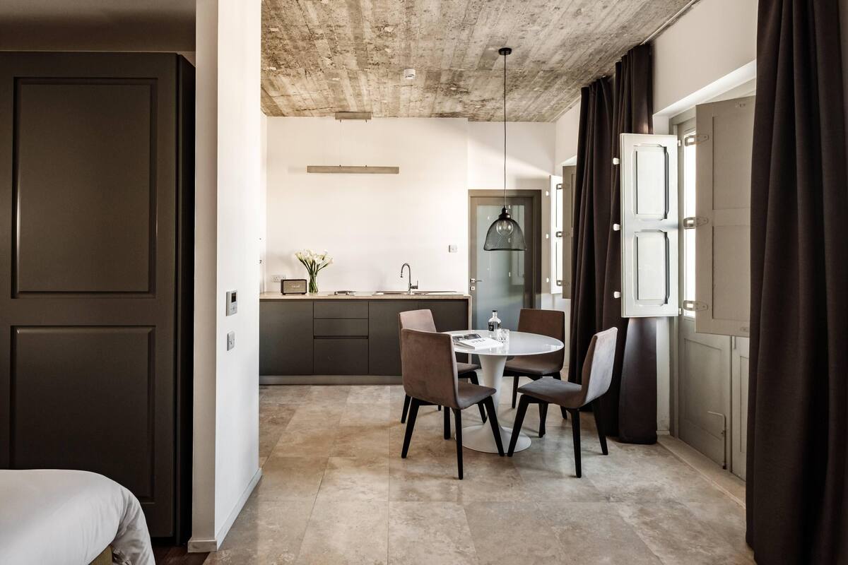 A modern kitchen with dark cabinetry, a round dining table, and a pendant light.