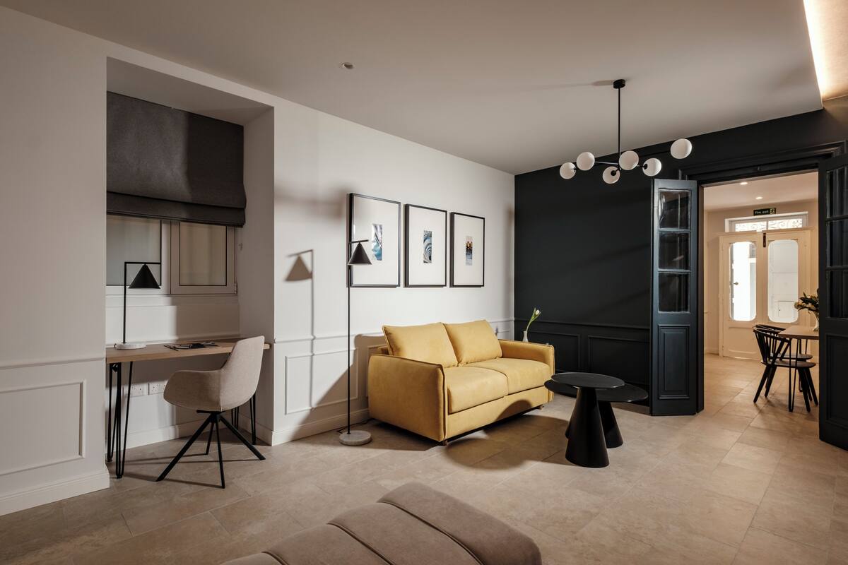 A modern living room with a sofa, a desk, and a dining area.