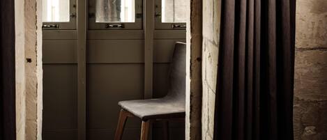 A room with a chair near a window, a door, and a curtain.