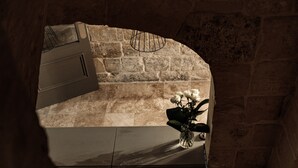 A stone wall with a curved archway, a white vase with flowers, and a metal rack on the wall. - 19 Rooms (Valletta)