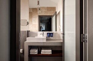 Un baño moderno con un lavabo blanco, un espejo y un perchero para toallas.