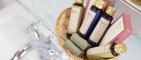 Una cesta de mimbre con diversos productos de baño Magena sobre un estante de vidrio.
