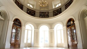 Una sala de lectura grande y circular, con techos altos, amplias ventanas de arco y un candelabro central.
