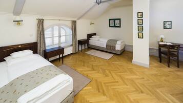 A bedroom with two beds, a desk, and a window with curtains.
