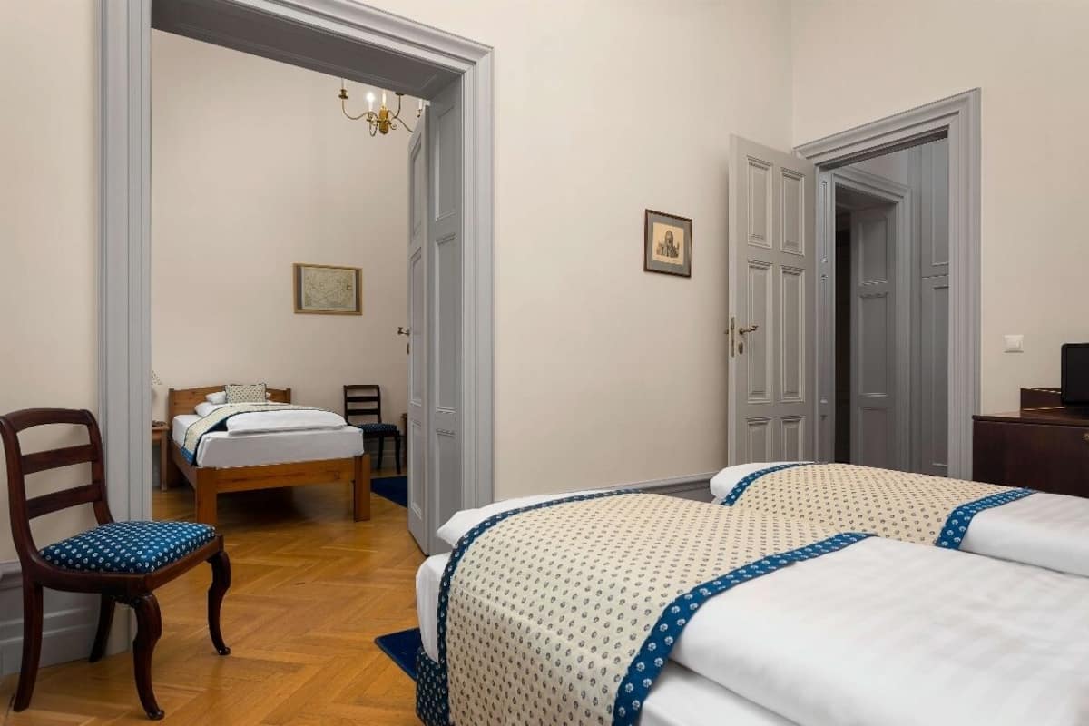 Un dormitorio con dos camas, una silla de madera, un escritorio y un armario.
