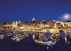 Un puerto deportivo con barcos amarrados, un paisaje urbano con edificios históricos y una imponente torre del reloj.
