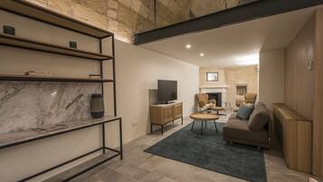 Una sala de estar moderna con un estante de mármol, un televisor, un sofá y una chimenea.