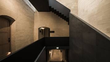 A modern interior with a staircase, a wooden door, and a small illuminated object on the wall.