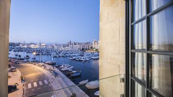 A view of a marina with numerous boats docked, a cityscape in the background, and a clear sky.