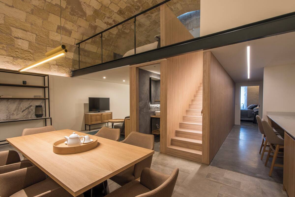 A modern interior with a dining area, kitchen, and staircase.
