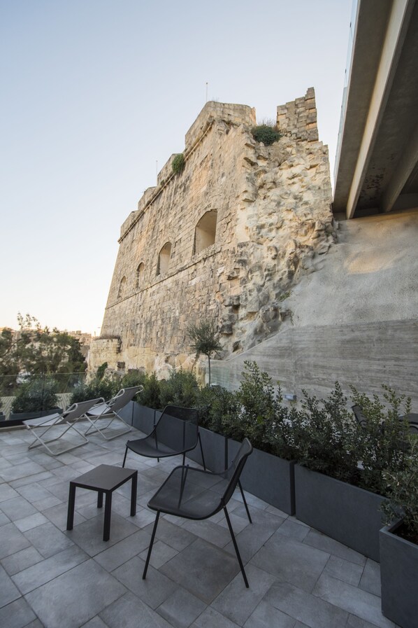 Un patio con muros de piedra, algunas sillas y una pequeña mesa.