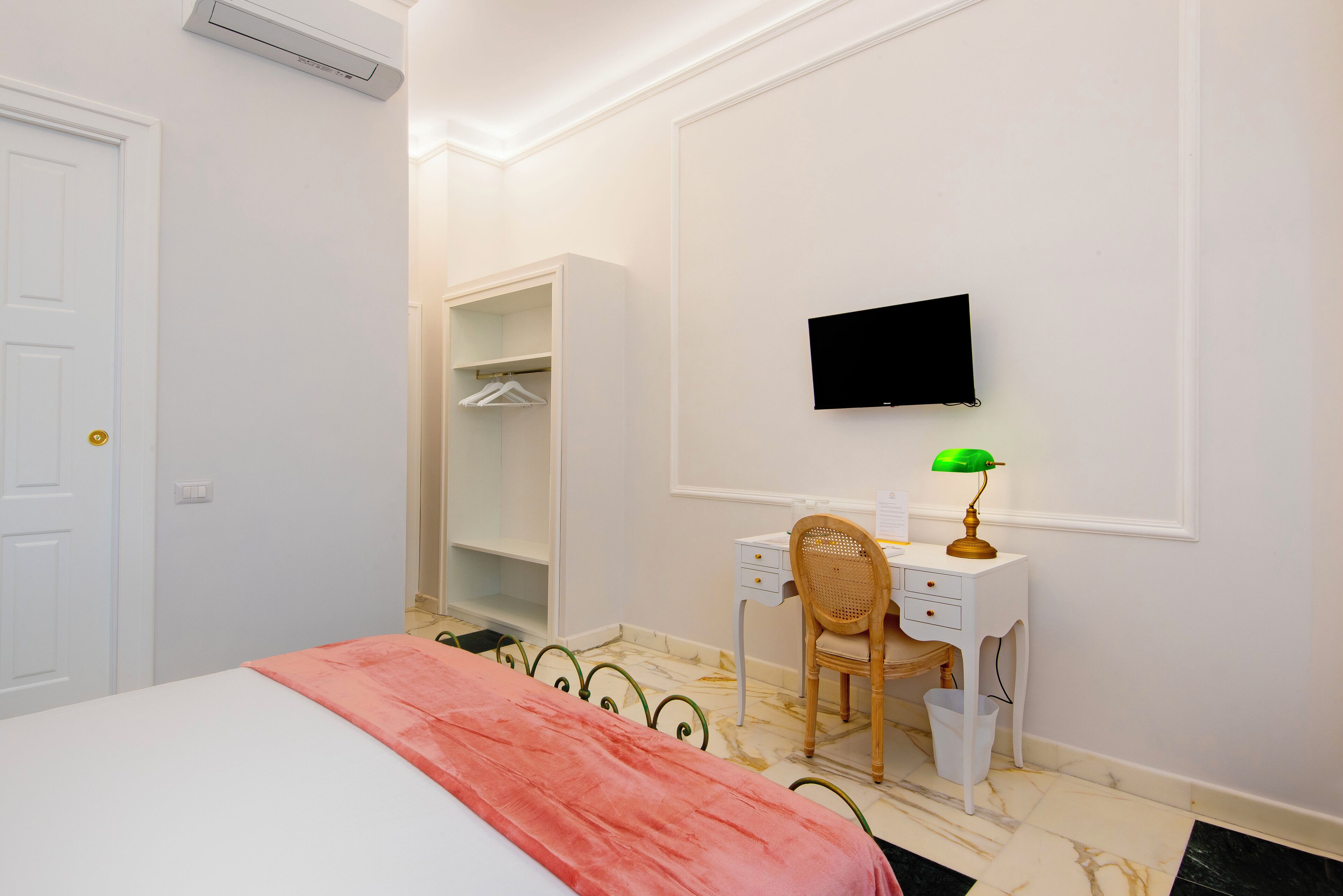 Een slaapkamer met een bed, een bureau, een stoel, een televisie en een kledingkast.