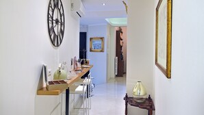 A hallway with a dining area featuring a wooden table, chairs, and a wall-mounted clock. - Residenza Borbonica (Naples)