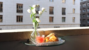 A balcony with a glass tray holding a vase of white flowers, a glass of pink drink, and a croissant. - Residenza Borbonica (Naples)