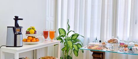 A breakfast setup with a coffee maker, fruit bowl, and glass of orange juice.