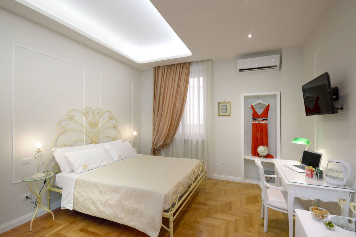 Ein Schlafzimmer mit Bett, Nachttisch, Lampe und Schreibtisch mit Stuhl.