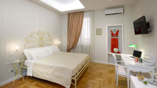 A bedroom with a bed, bedside table, lamp, and a desk with a chair. - Residenza Borbonica (Naples)