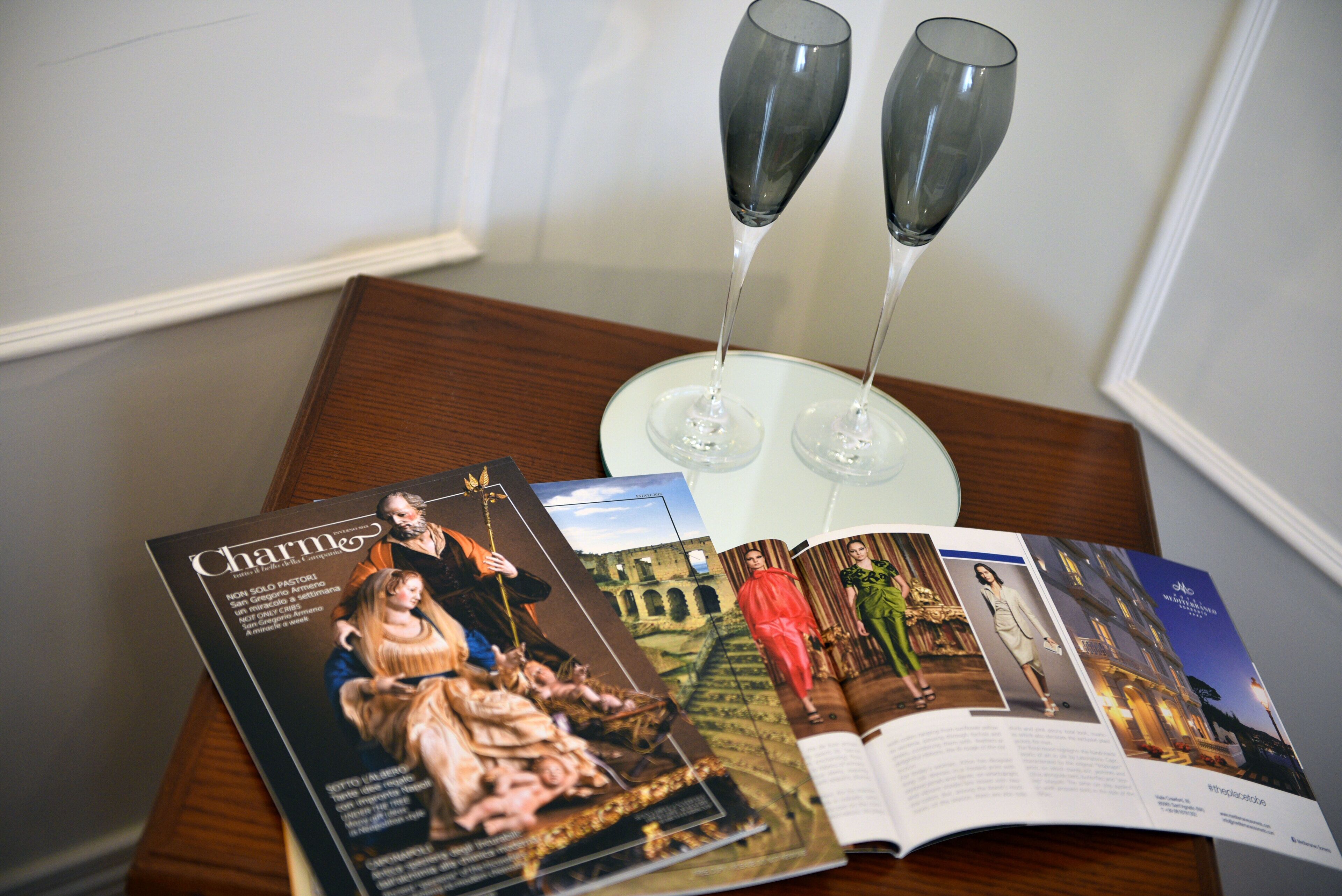 A magazine open on a wooden table with two champagne flutes.