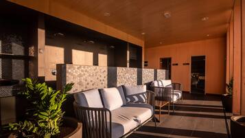 A modern indoor seating area with a sofa, chairs, and a potted plant.