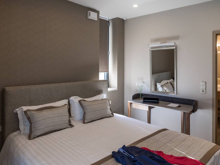 Une chambre d’hôtel avec un grand lit, une table de chevet, un miroir et une vue sur la salle de bain.