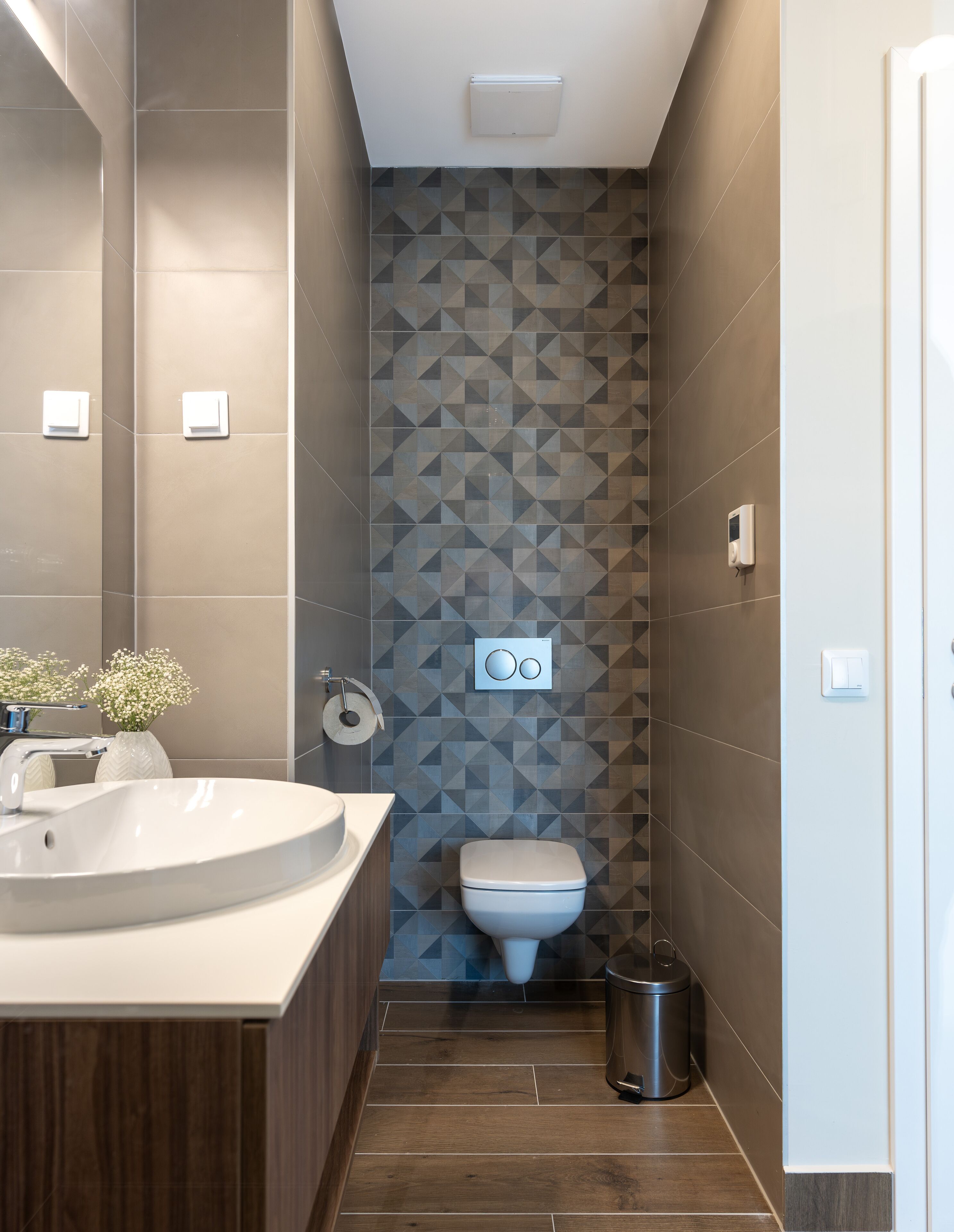 Een moderne badkamer met een groot wastafel, toilet en een prullenbak.