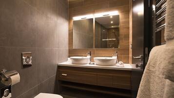 A modern bathroom with two sinks, a large mirror, and a towel rack.