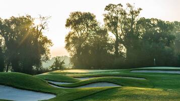 Un campo de golf con búnkeres de arena y árboles al fondo.