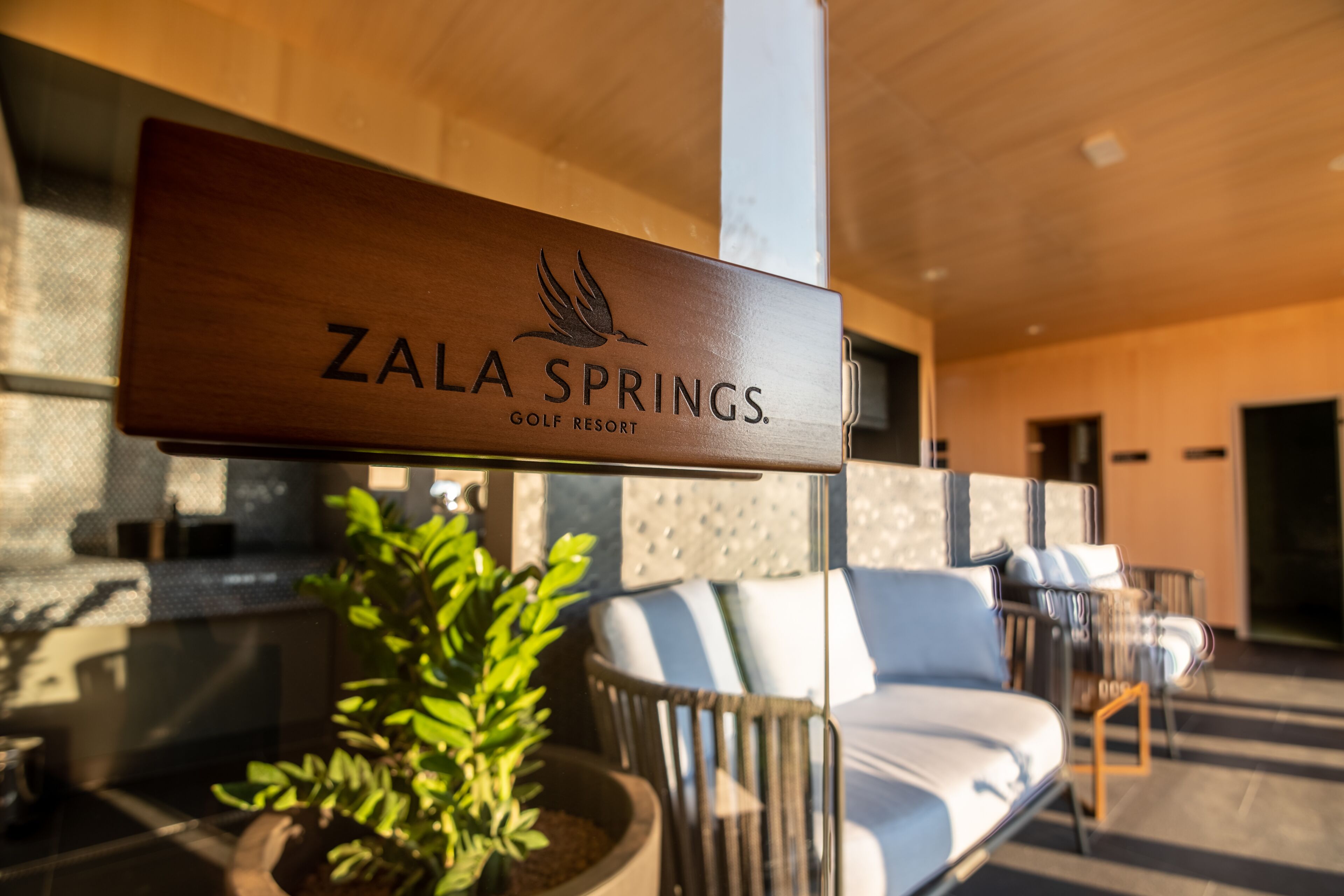 A wooden sign with the text "ZALA SPRINGS GOLF RESORT" and a bird logo.