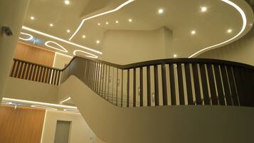 A modern interior with a curved staircase, recessed lighting, and a wooden panel wall.